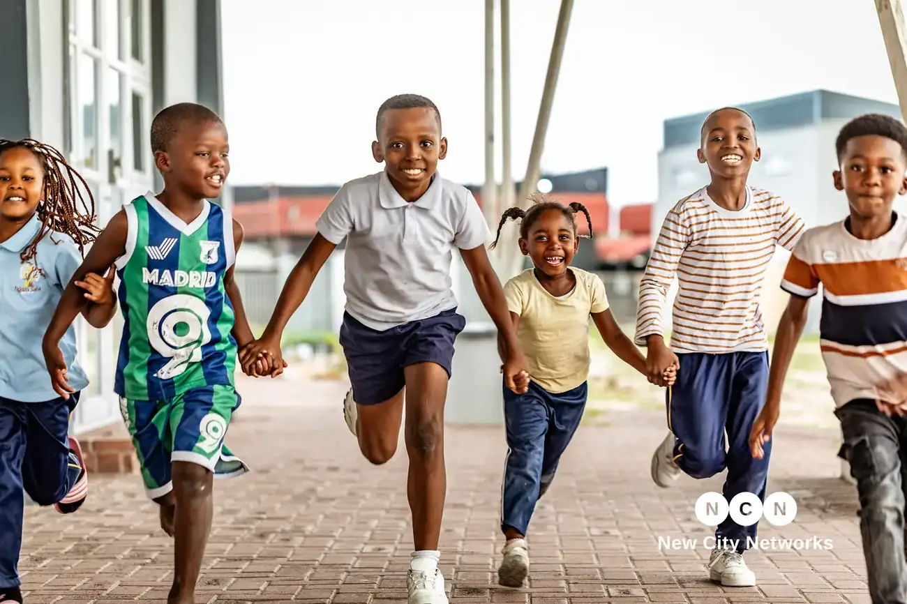 Nguzo Saba learners running together along the school walkway, hand in hand